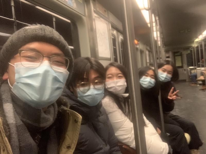 Students sitting on a Boston subway smiling at camera.