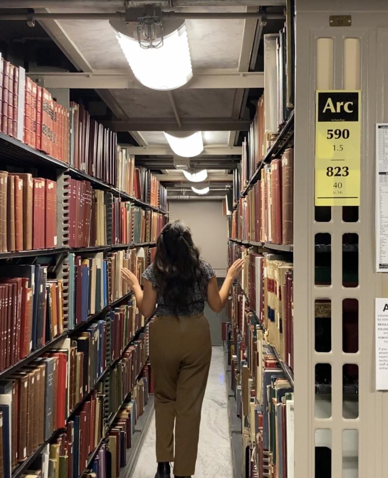 A woman walks through a library at Harvard.