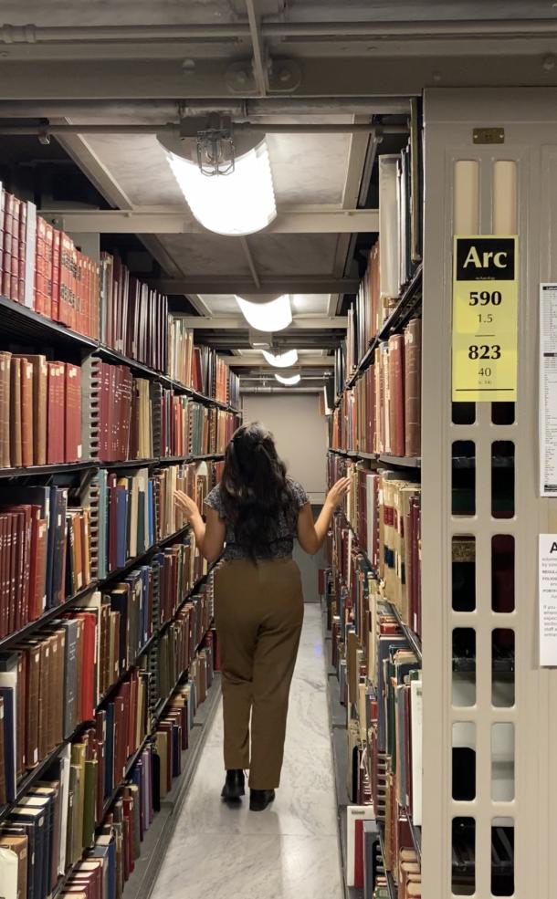 A woman walks through a library at Harvard.