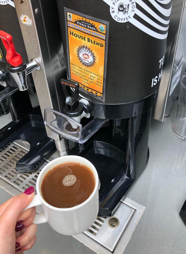 Photo of a cup of hot coffee in front of the dispenser
