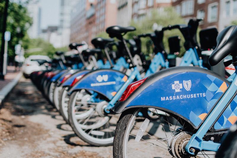 A group of blue bicycles all neatly lined up near each other.