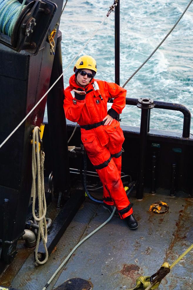 Writer wearing daily personal protective equipment, blowing a kiss while standing on deck