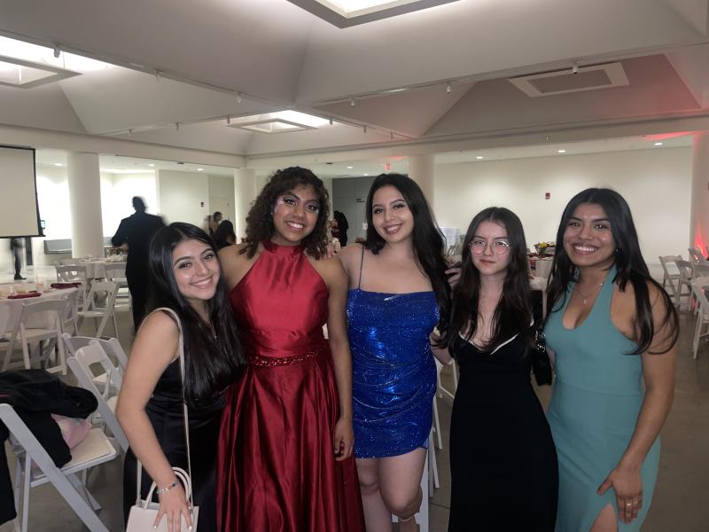 5 students smile for a picture. They are wearing formal dresses