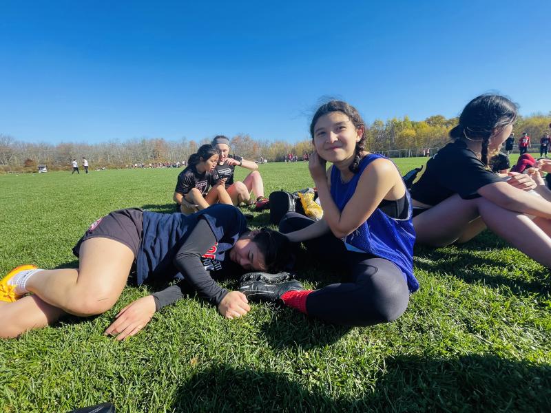 Erika and a friend resting on the grass during frisbee practice