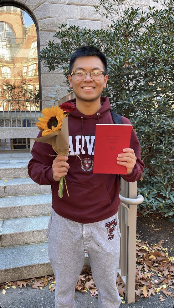 Picture of Raymond holding a sunflower and a Red Book.