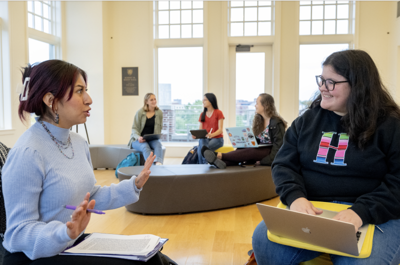 Image of two people sitting and talking to each other, with three people talking in the background