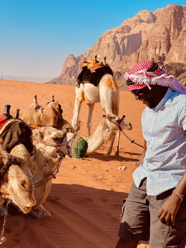A photo of writer admiring a camel in the desert