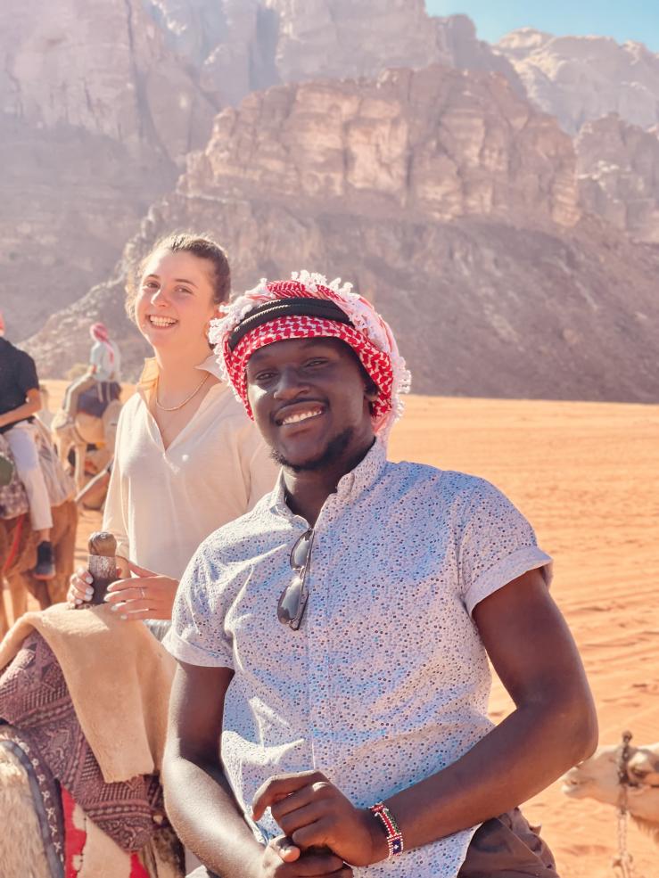 A photo of writer and another friend on camels in the desert