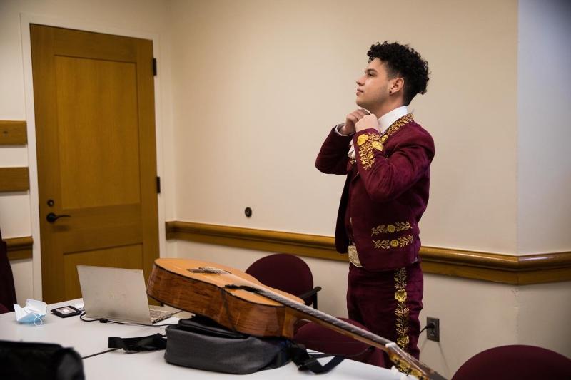 A mariachi performer fixing their bow. There is a guitar on the table in front of them.