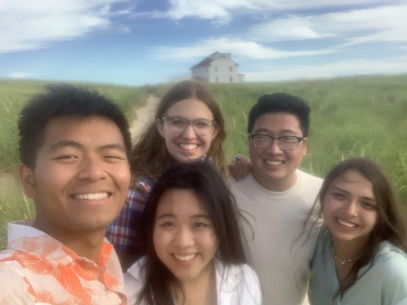 A selfie of Raymond and his four friends in front of a house and greenery