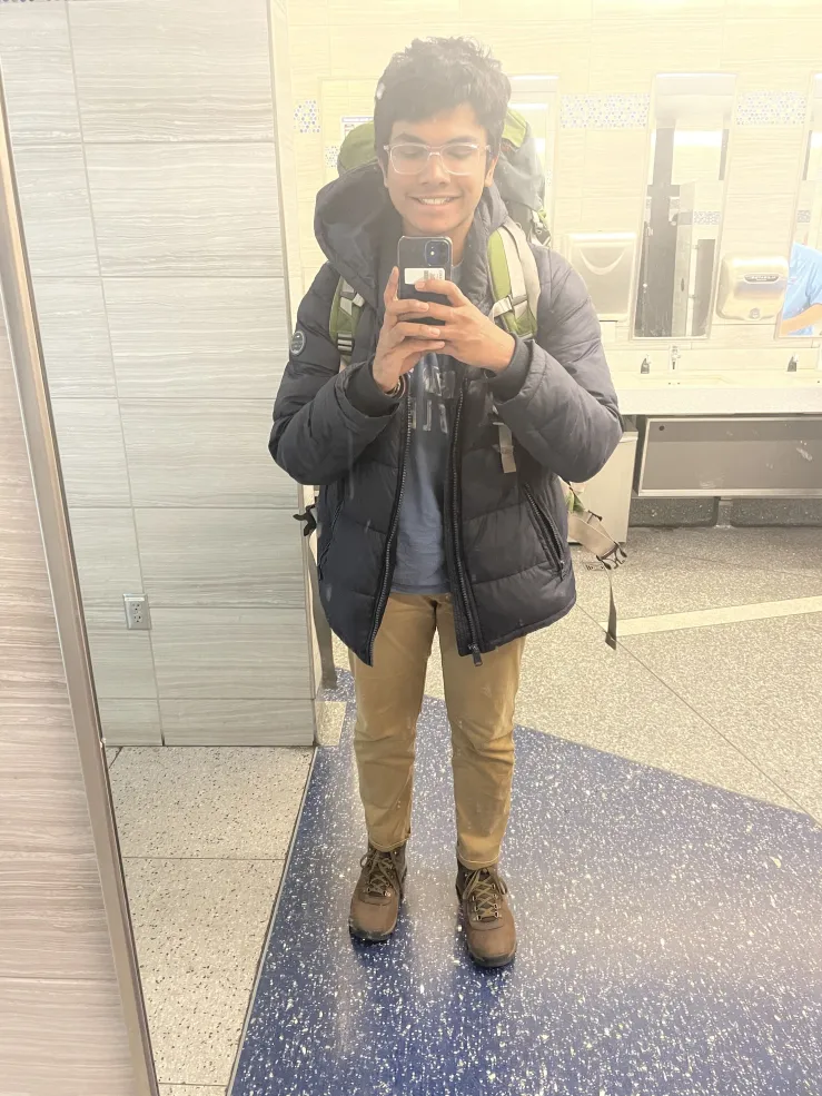 Image of Rafid at the airport wearing an 85L backpack, taking a picture in the mirror.