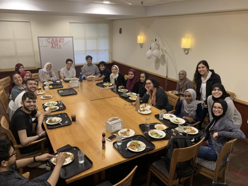 A large group of muslim students sitting around a dinner table