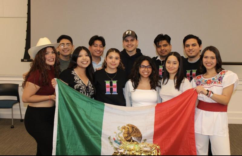 An image of the 11 board members for RAZA of the 2023 year.  They are holding up a Mexican flag. 