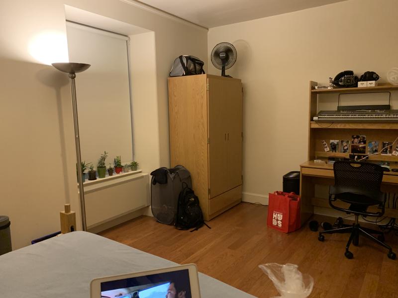 Dorm room with wardrobe, desk, chair, window and lamp