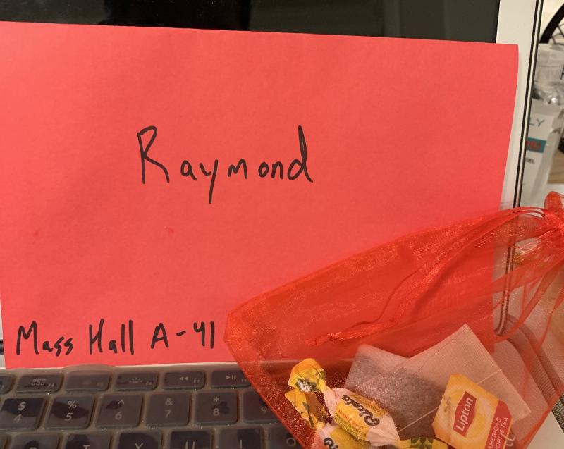 Picture of a red envelope with "Raymond" and "Mass Hall A-41" written on it sitting behind a red bag with cough drops and tea bags.