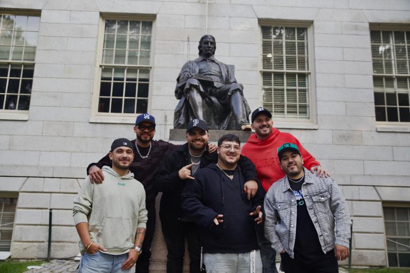 Grupo Frontera band members posing in front of the John Harvard statue. 