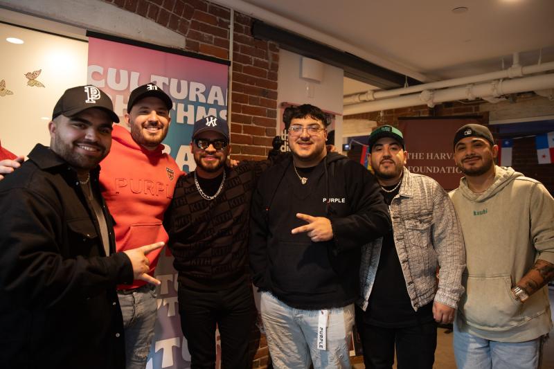 Picured are the six band members of Grupo Frontera, posing inside of the Harvard Foundation reception space. Some members are holding up peace signs. 