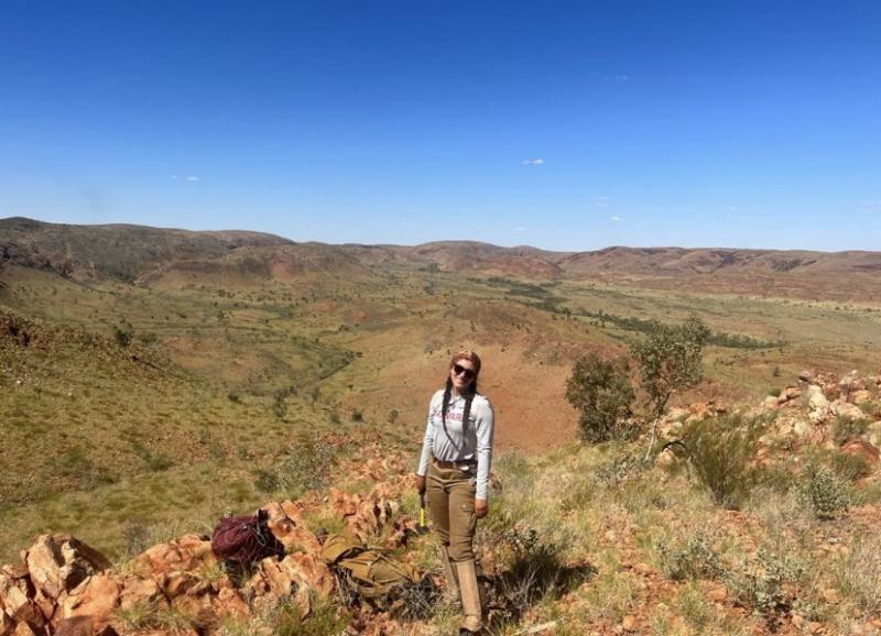 Image of me smiling atop a hill, with sprawling outback hills behind me. 