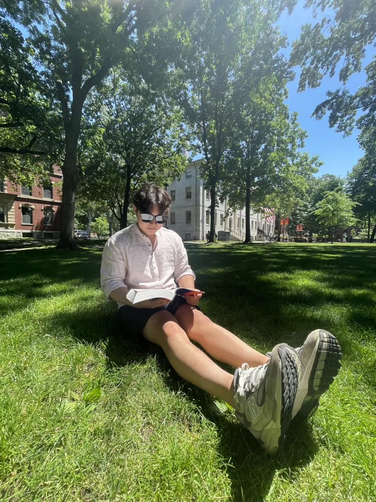 David sitting on the grass reading a book
