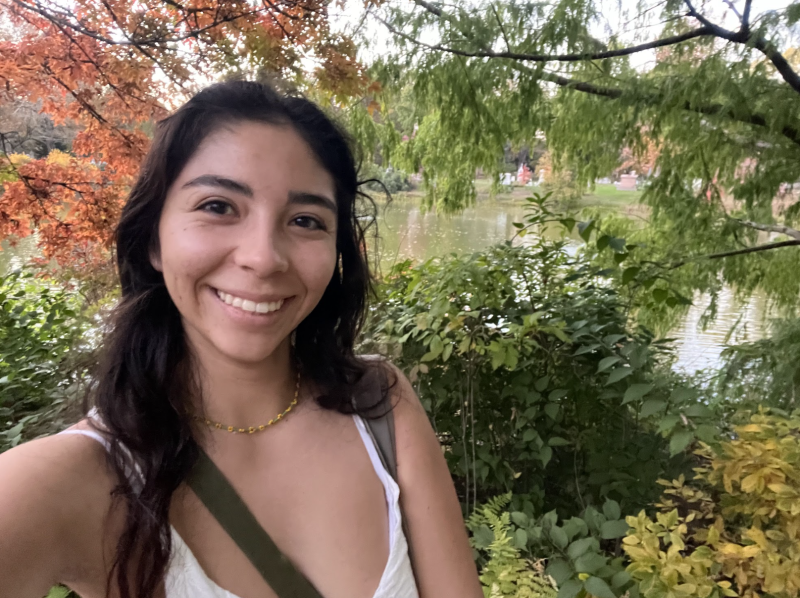 Adriana taking a selfie surrounded by colorful leaves and a body of water