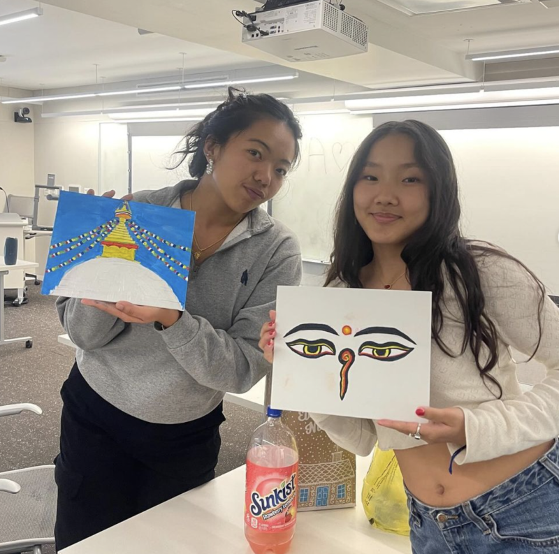 two students posing with their paintings