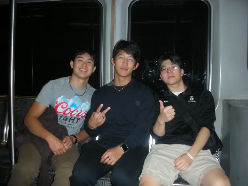 Three boys posing for a photograph on a subway