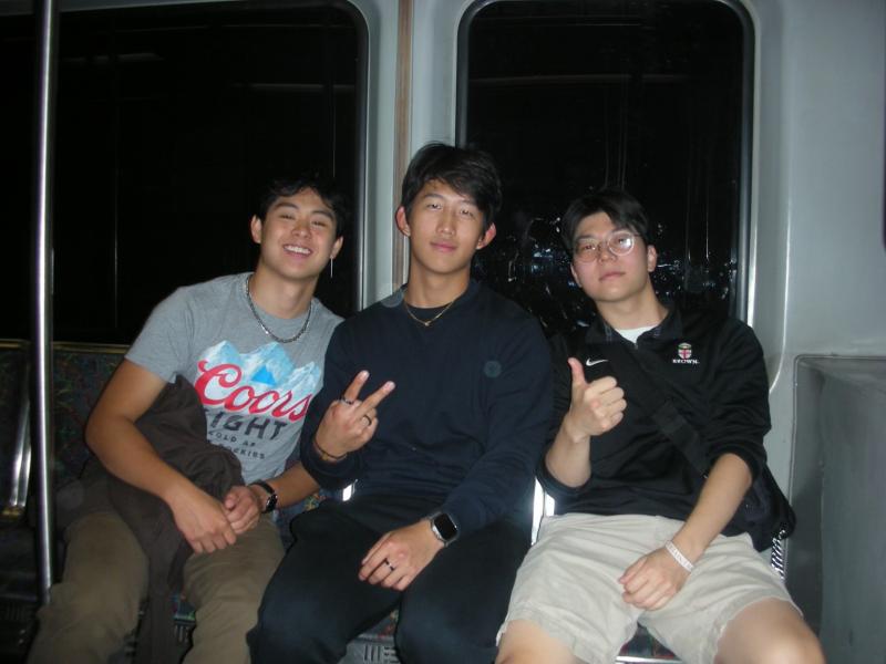 Three boys posing for a photograph on a subway