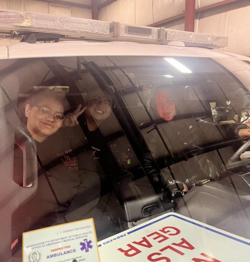 Three people sitting in ambulance and posing for a picture
