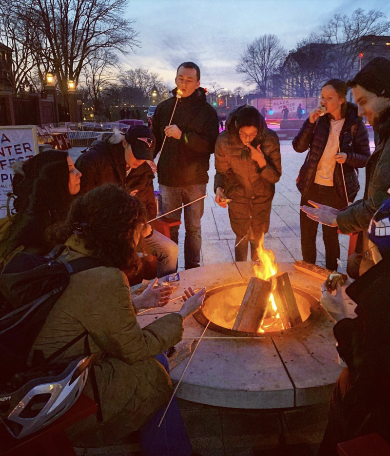 Students eating marshmallows around the bonfire at Science Center Plaza