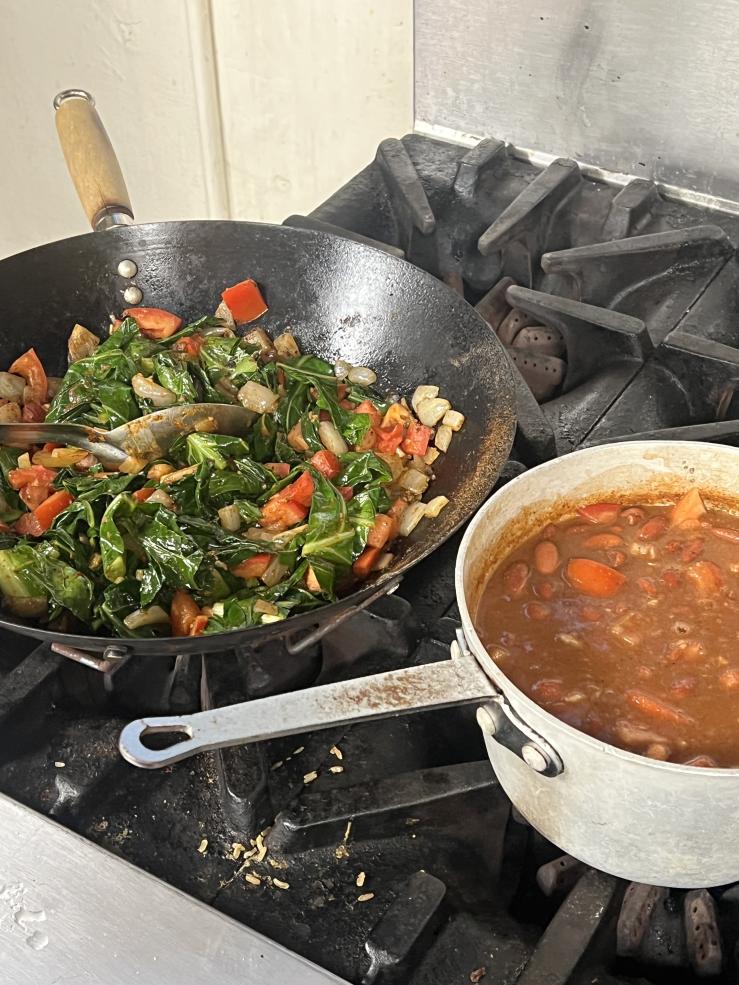 Image of a pot with rich, red vegetable stew and a wok beside it with stir-fried vegetables.