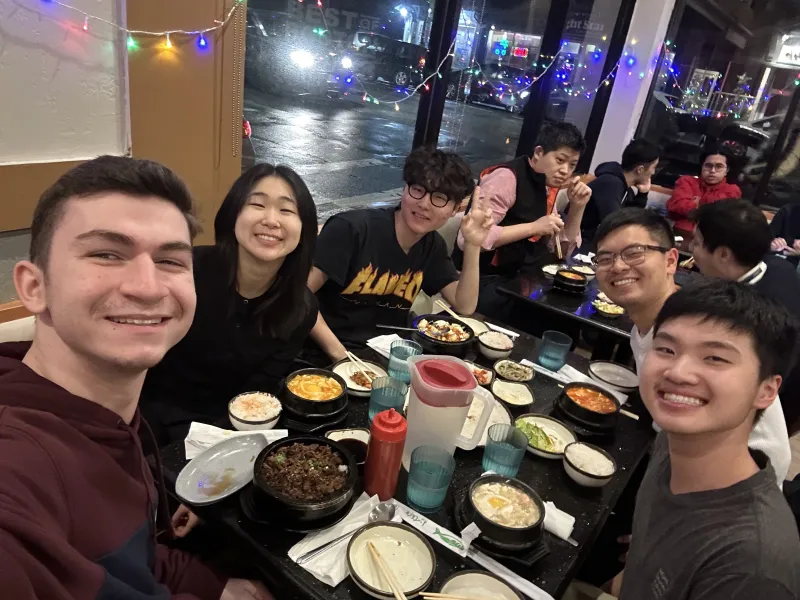 Picture of Raymond and his friends sitting around a table having a meal.