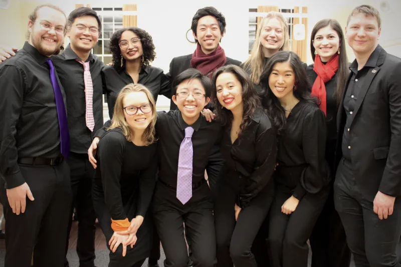 Group picture of Raymond and his friends in all-black concert attire and colorful accents smiling at the camera.