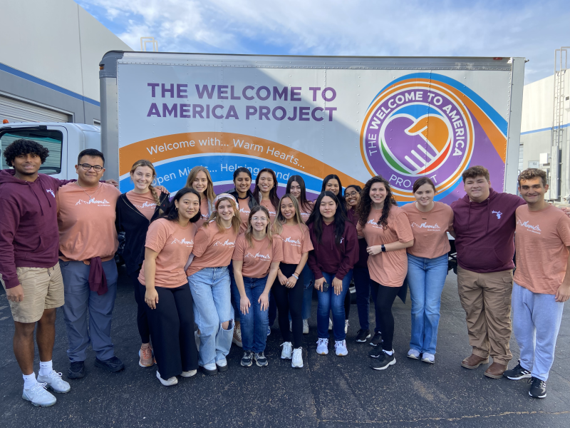 Group photo standing in front of The Welcome to America Project Truck