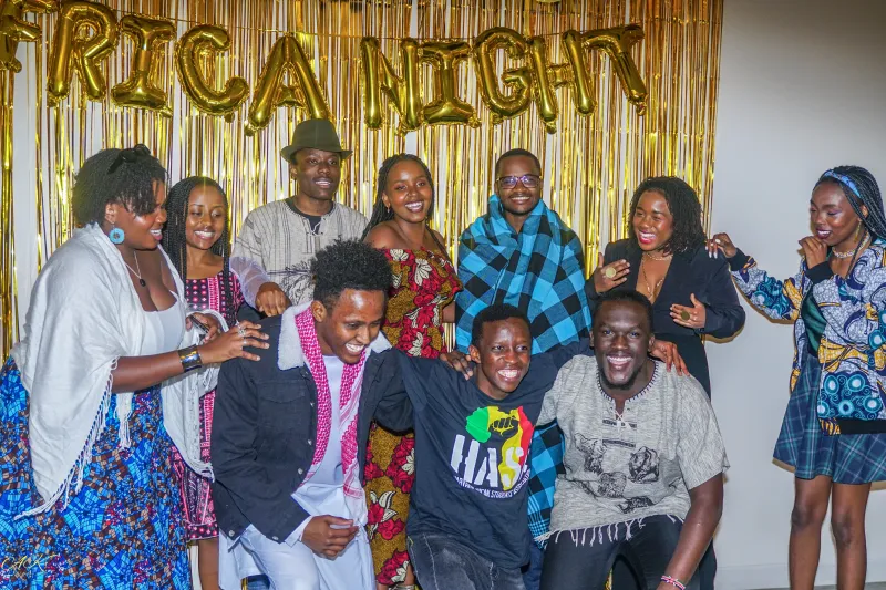 A photo of smiling students below a banner written "Africa Night"