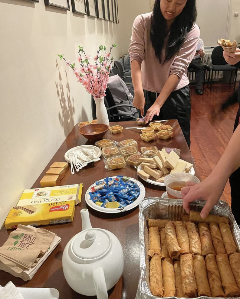 A picture of a brown table with food, including egg rolls and tea.