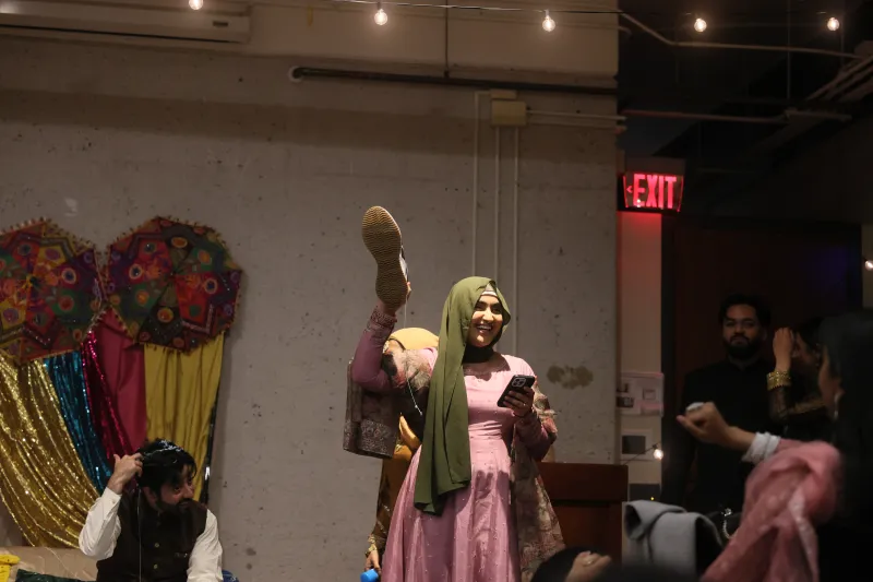 An executive member of the club, Laiba Khan, holds a shoe during the Jhoota Chupai tradition.