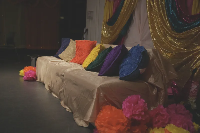 A couch decorated with bright pillows with a backdrop placed behind it by the Harvard College Pakistani Students Association, led by Hana Rehman..