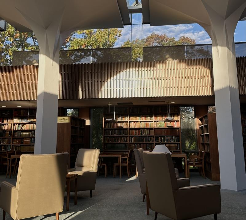 This is a picture of the Leverett House library, there are some singular couches, study tables, and shelves filled with books around.