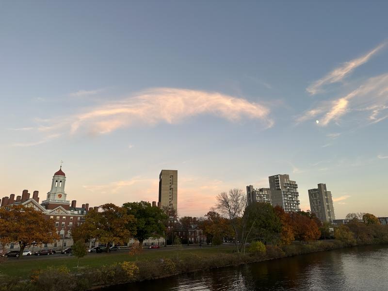 A picture taken from Week's Bridge showing a bit of the Charles River, some of Dunster House and other residential buildings during a sunset. 