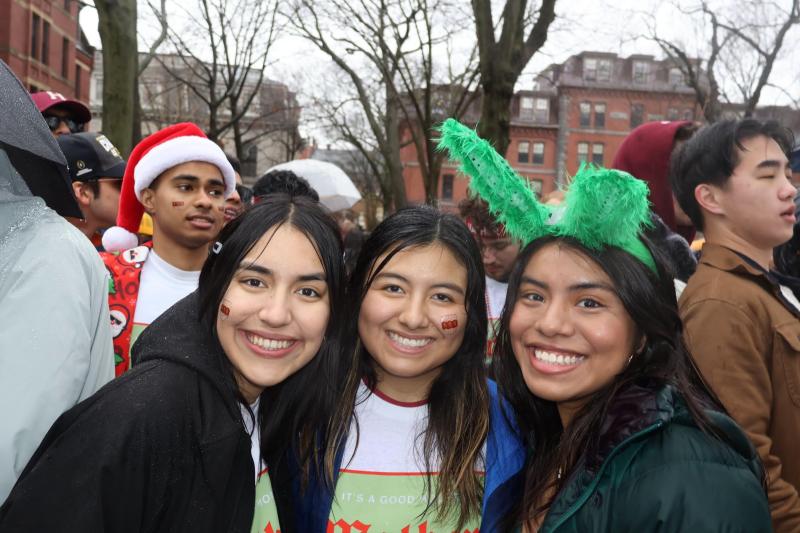 Three girls facing the camera and smiling, outside, in Harvard Yard.