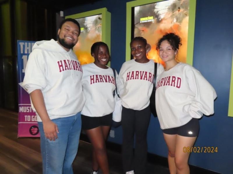 4 people posing in front of a movie poster.