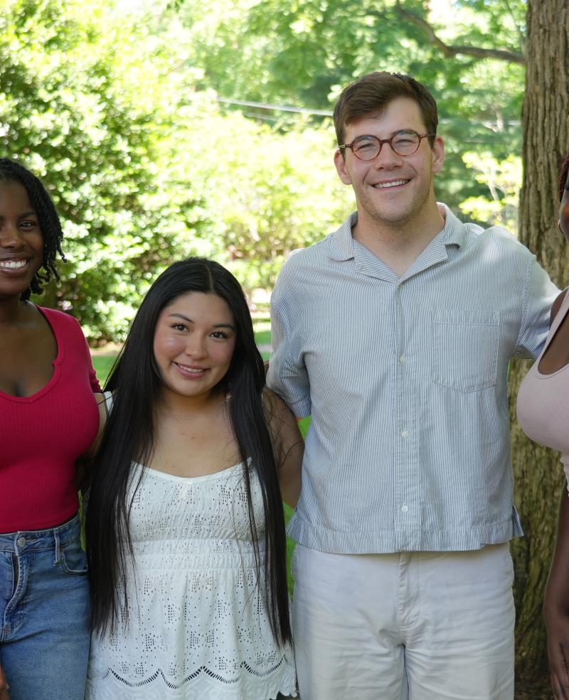 A group of four students serving as Summer Student Coordinators, standing in front of a tree. 