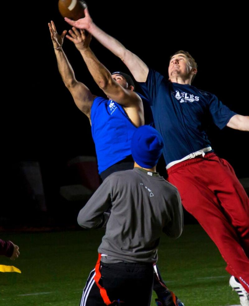 Four people are playing flag football at night