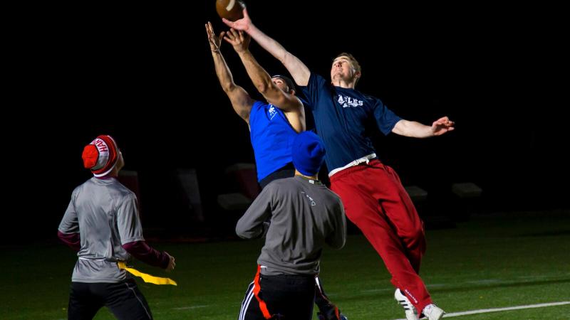 Four people are playing flag football at night