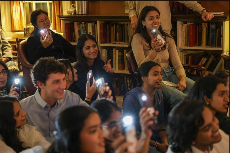 Students watching performances with their phone flashlight on