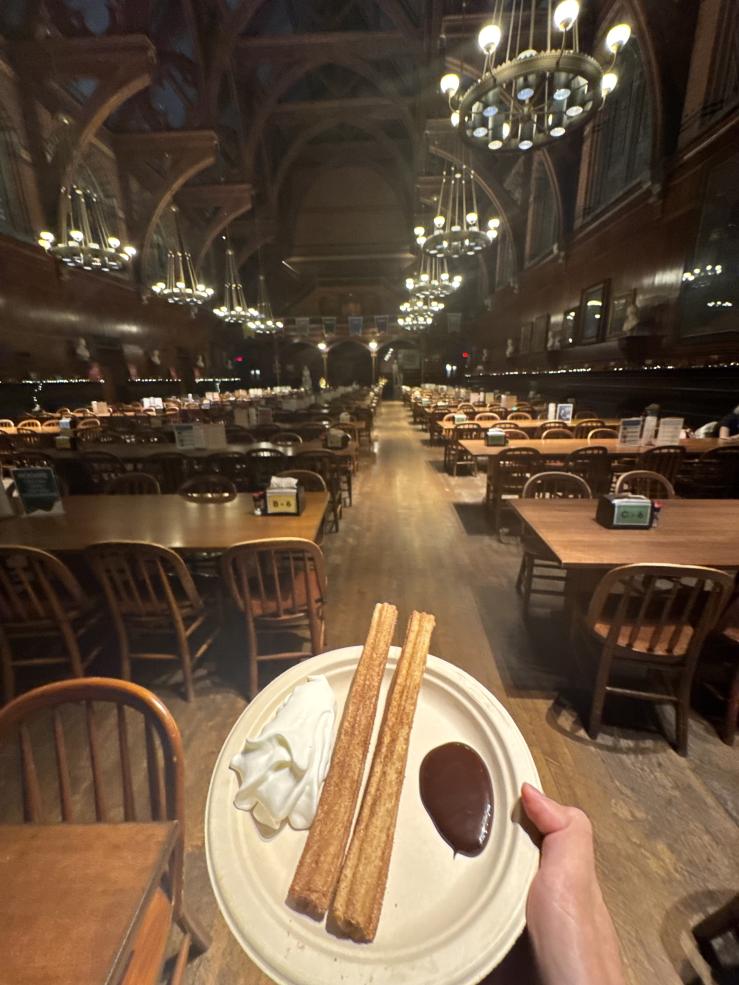Churros with whipped cream and chocolate sauce are seen with Annenberg Hall in the background.