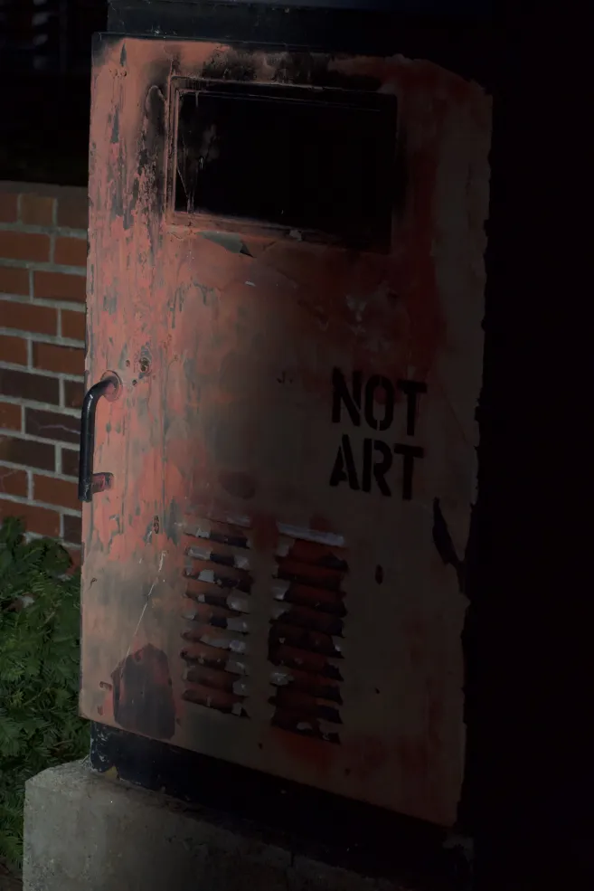 Picture of a red public mail delivery box with the words "NOT ART" painted on it. 