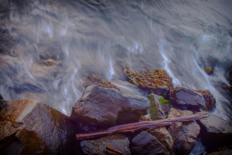Picture of water rushing over rocks on a rocky shore.