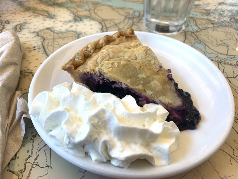 Picture of a slice of blueberry pie with whipped cream topping on the slide.