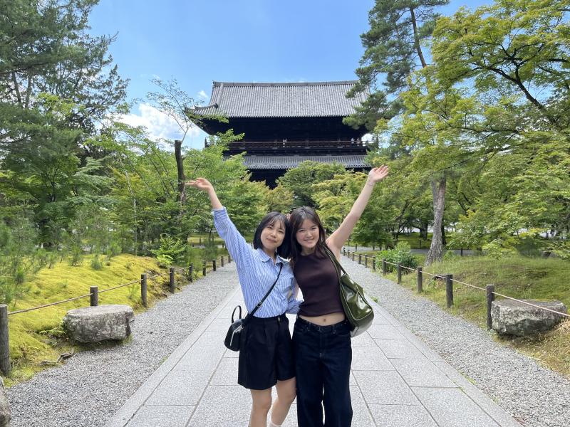 2 students posing in front of a temple